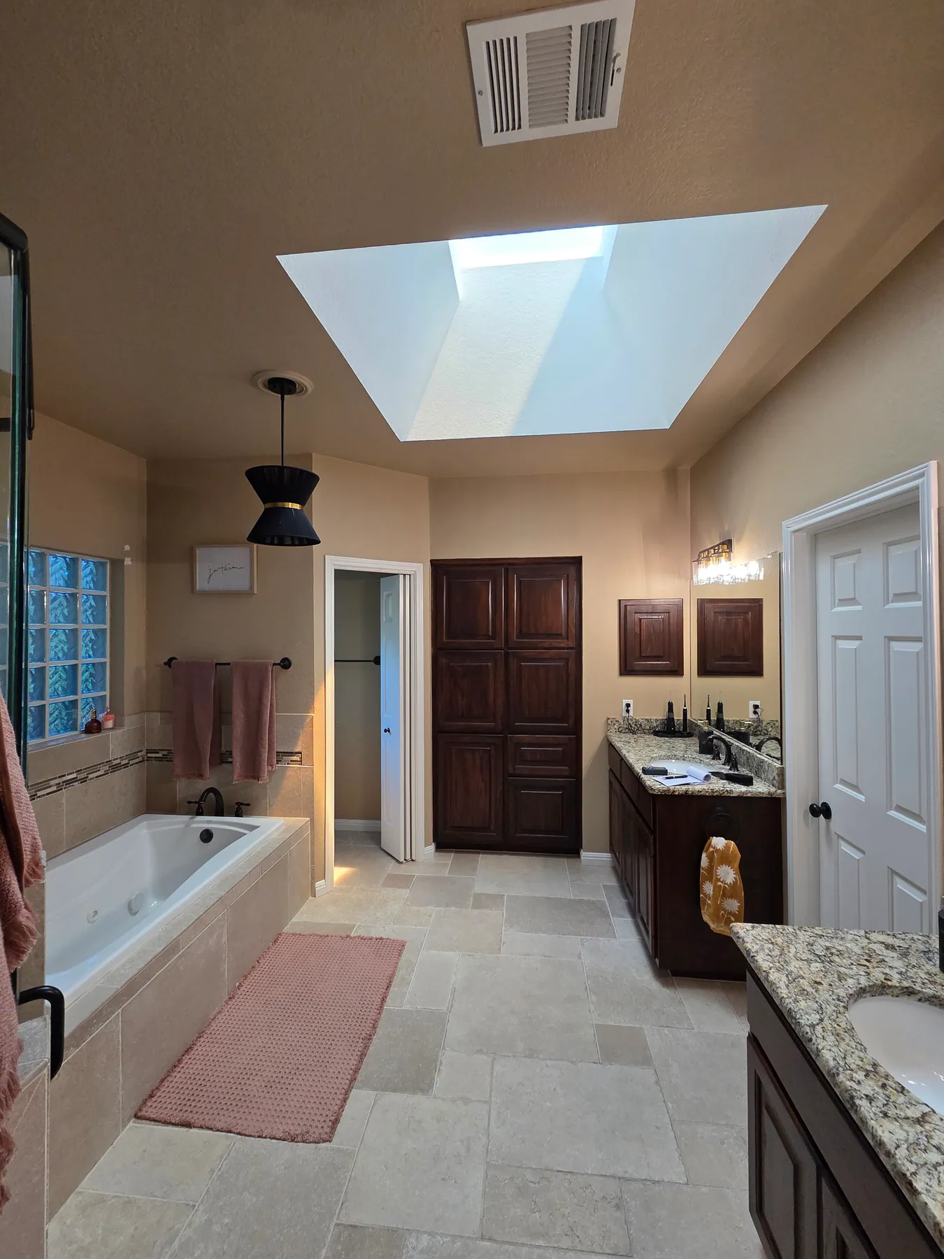 Finished Austin bathroom with painted walls, vanity, tile, and skylight