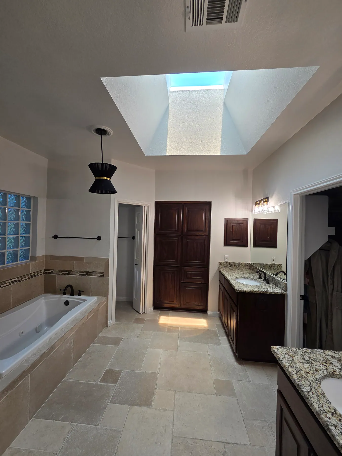 Austin bathroom walls and ceiling around a tub, tile, vanity, and skylight