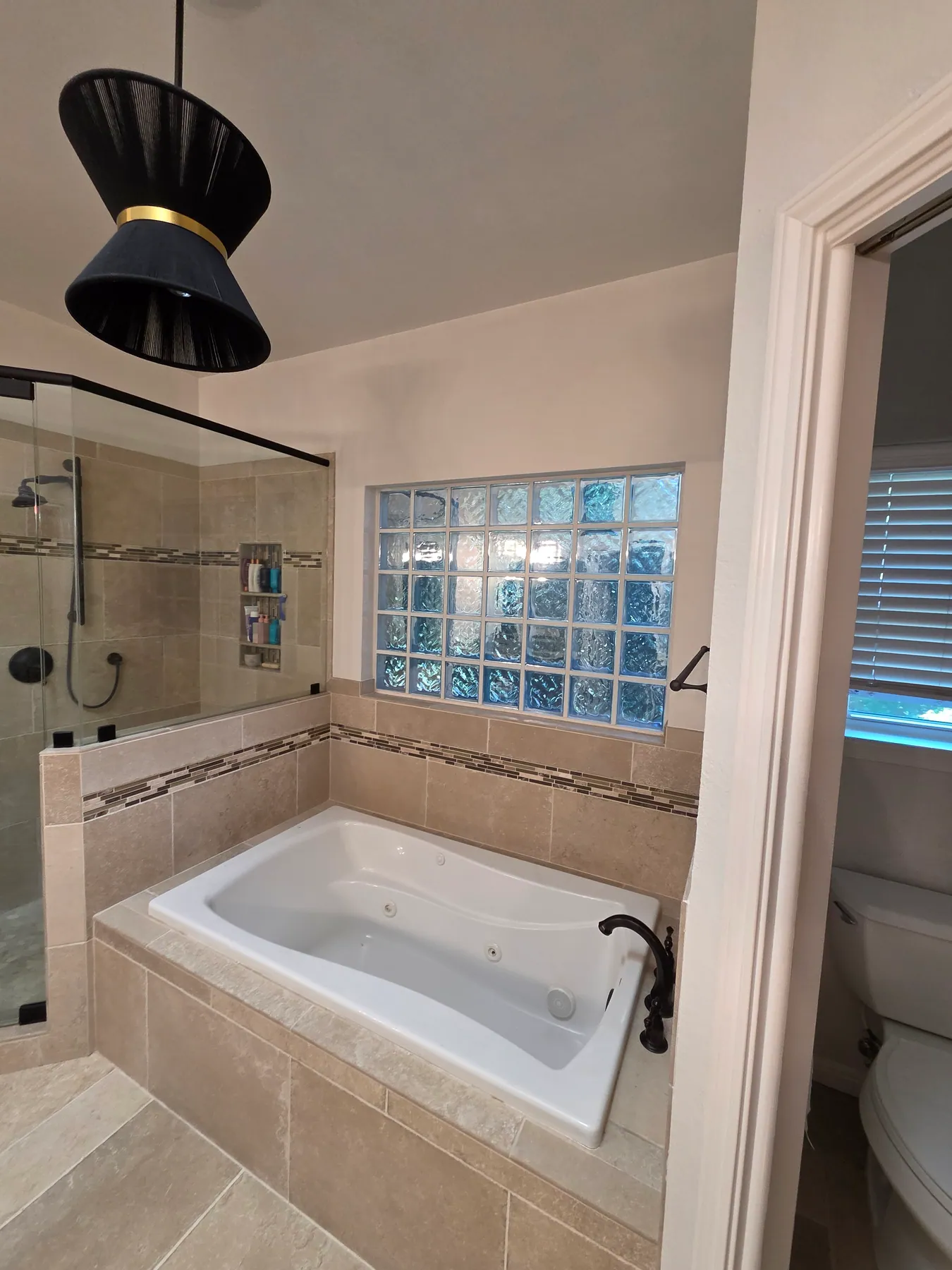 Bathroom shower and tub area with glass enclosure and tile surround