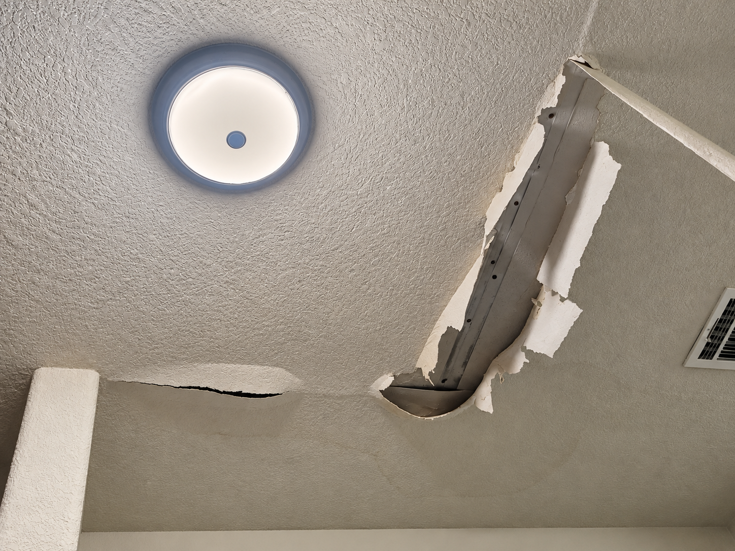 Damaged textured drywall ceiling with a large broken section in an Austin home