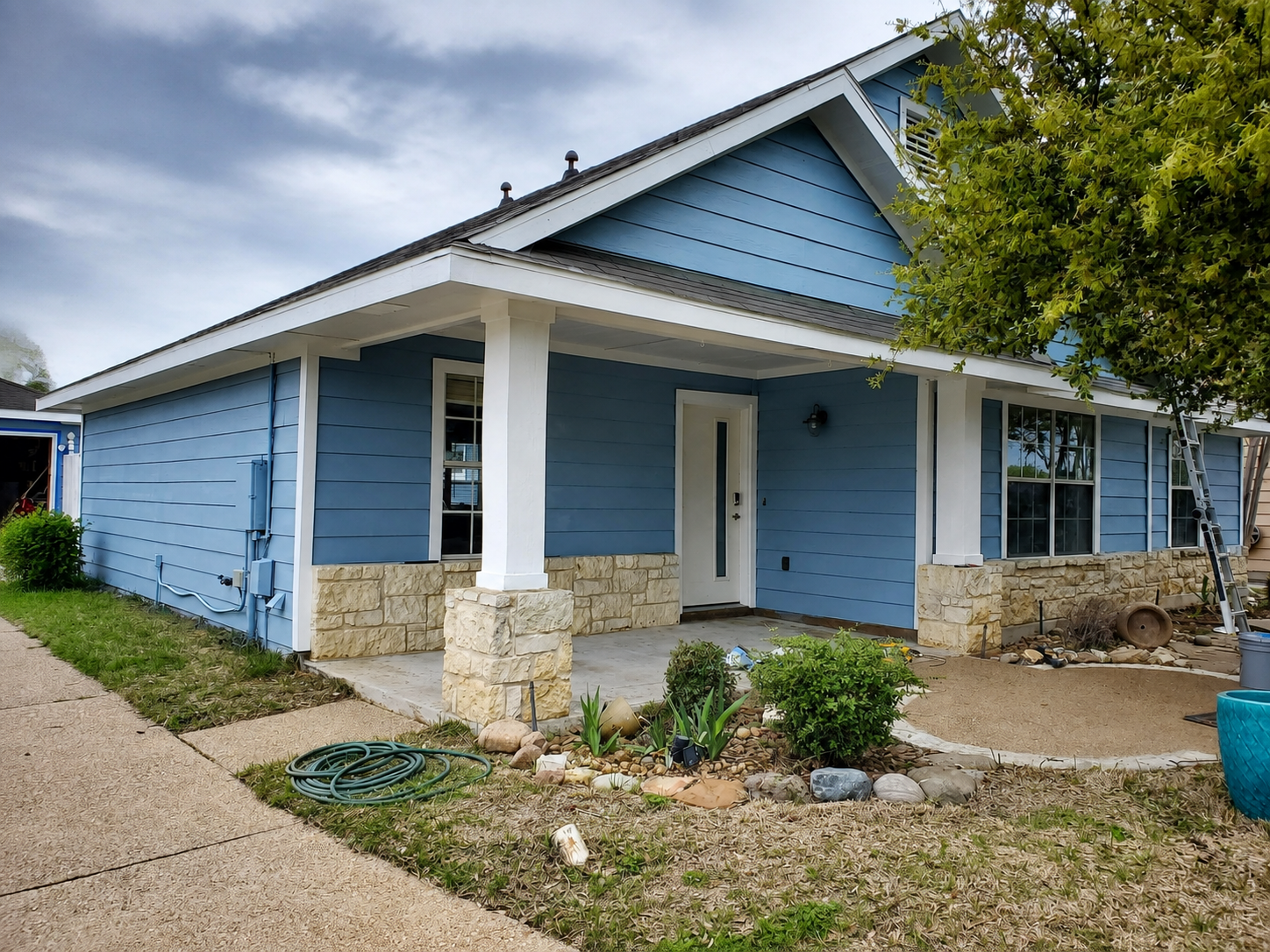 Completed light blue exterior house painting project with white trim in Austin