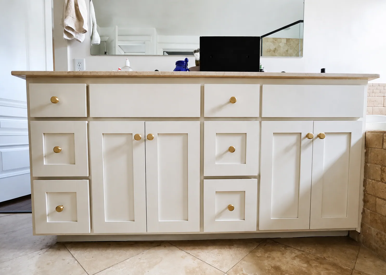 Freshly painted light cabinets with gold hardware in an Austin area bathroom
