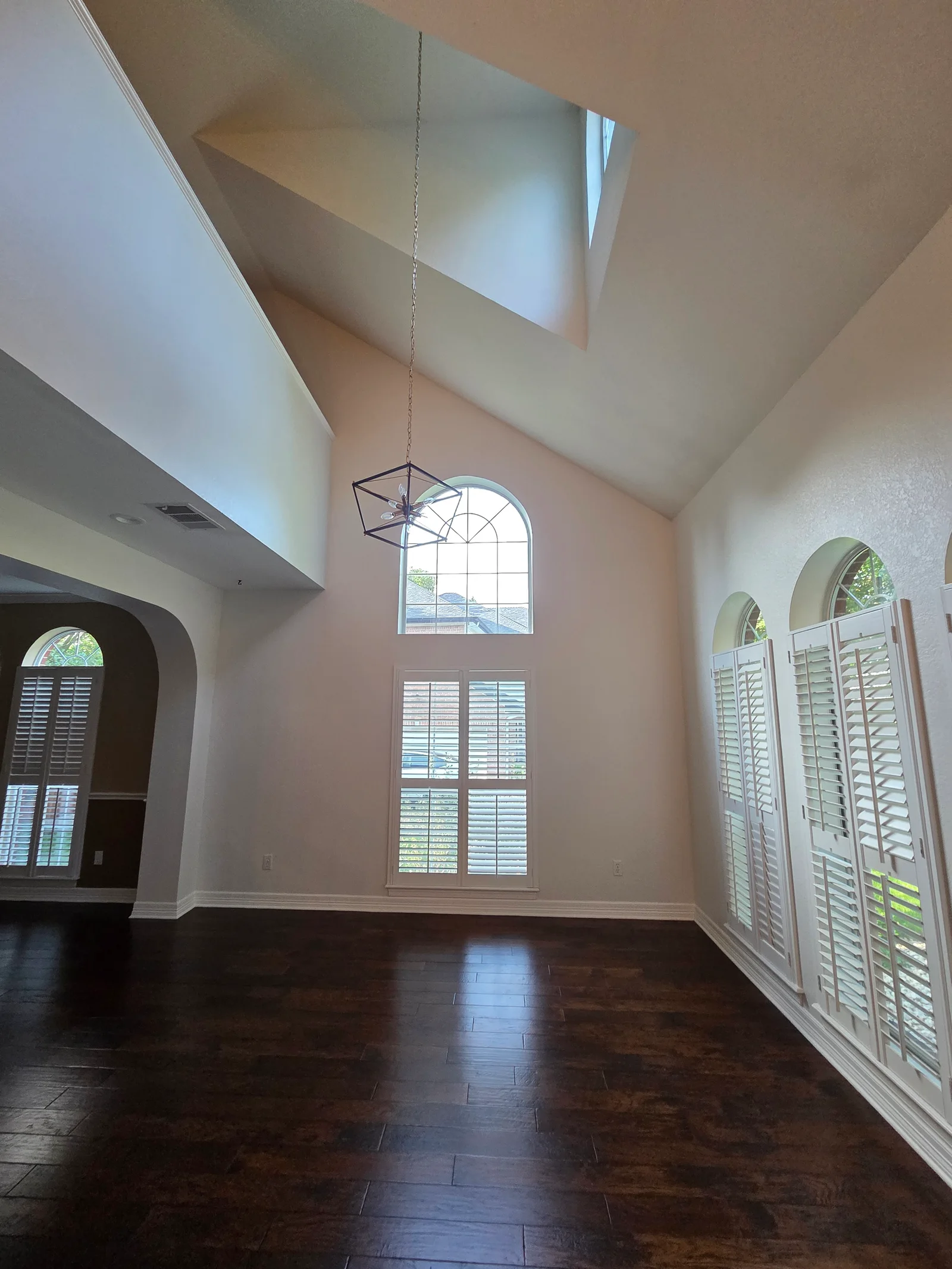 Finished white walls and high ceiling around tall Round Rock windows