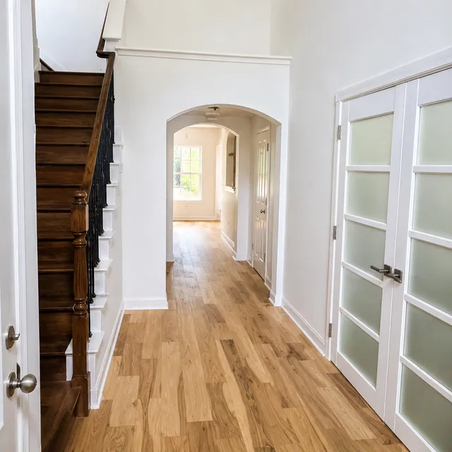 Remodeled foyer with wood flooring, staircase, and glass-paneled interior doors