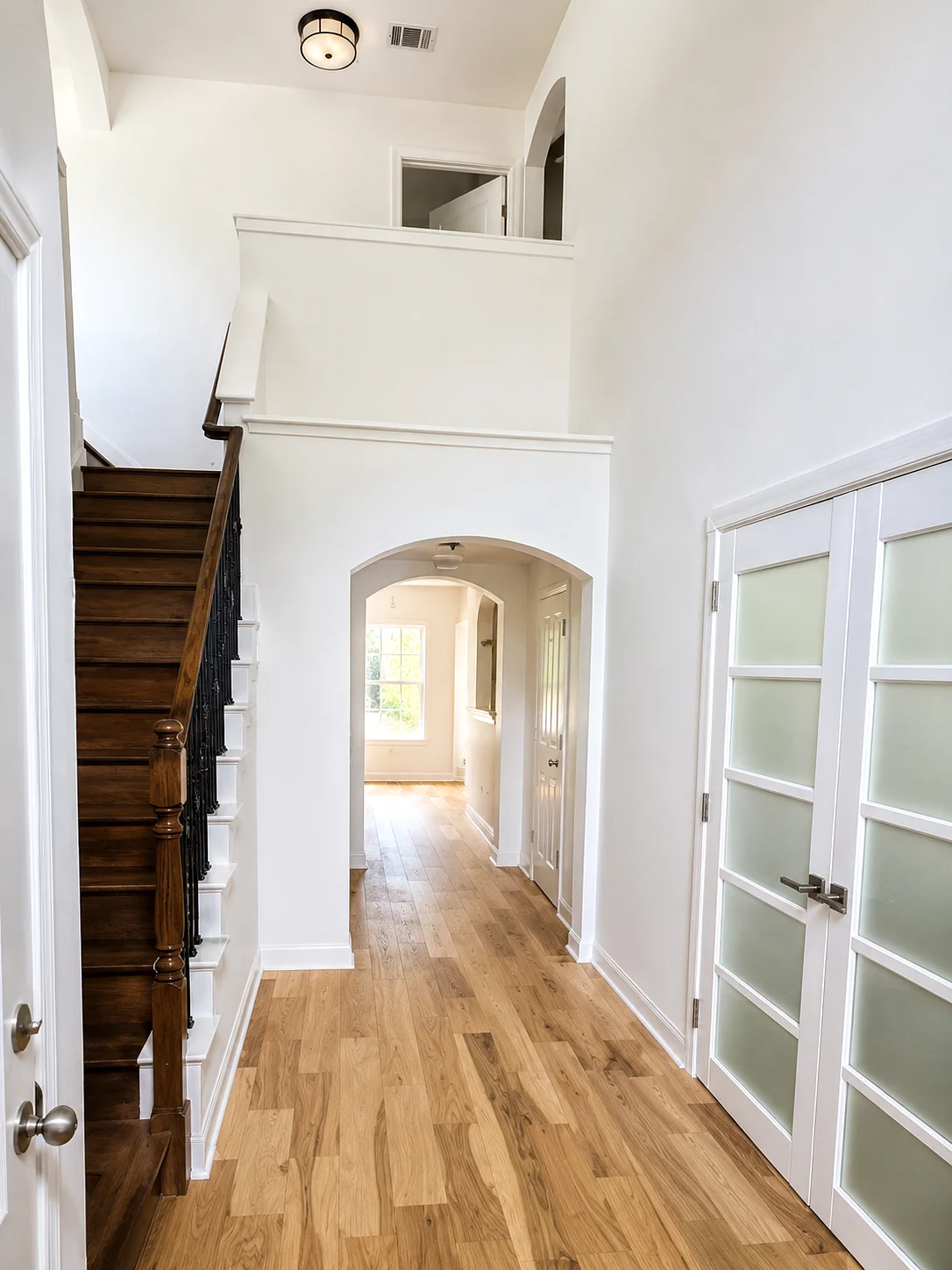 Bright finished Austin home entry with freshly painted walls, staircase, and wood flooring