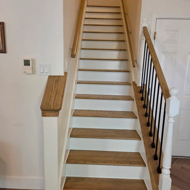Renovated staircase with wood treads, white risers, and black balusters