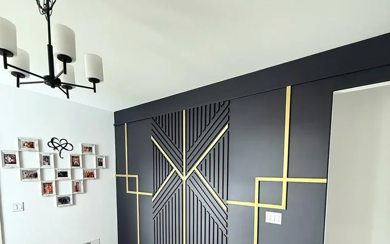 Black geometric accent wall with gold trim and decorative wood slat pattern