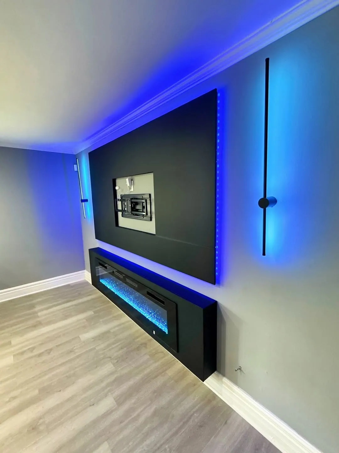 Black media and fireplace feature wall with blue and purple accent lighting