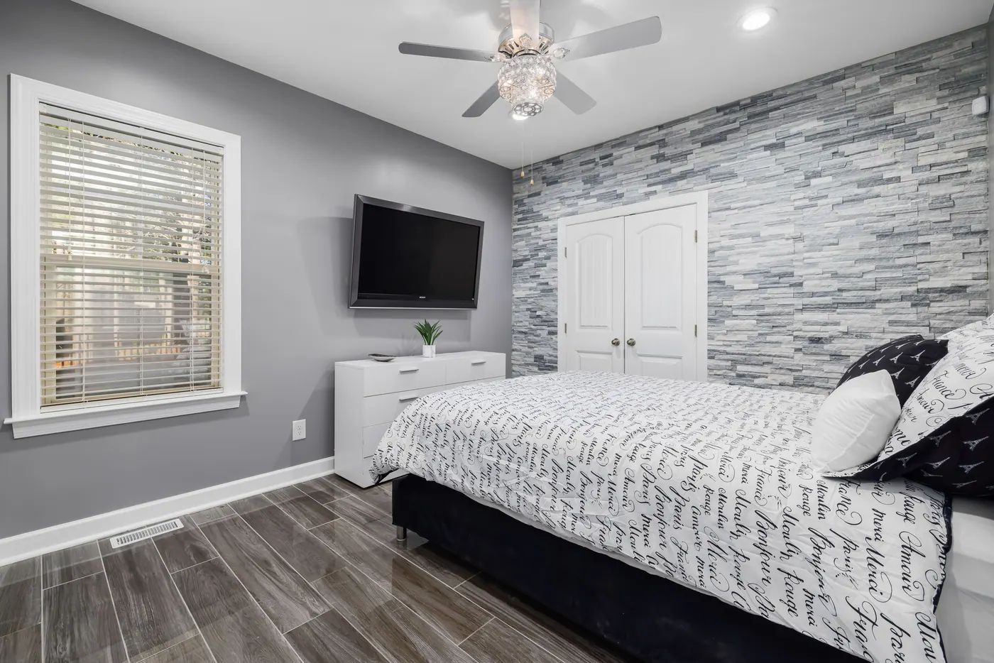 Bedroom with a gray stone accent wall and clean trim details