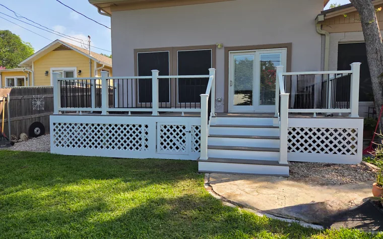 Finished backyard deck with white railings, black balusters, stairs, and lattice skirting