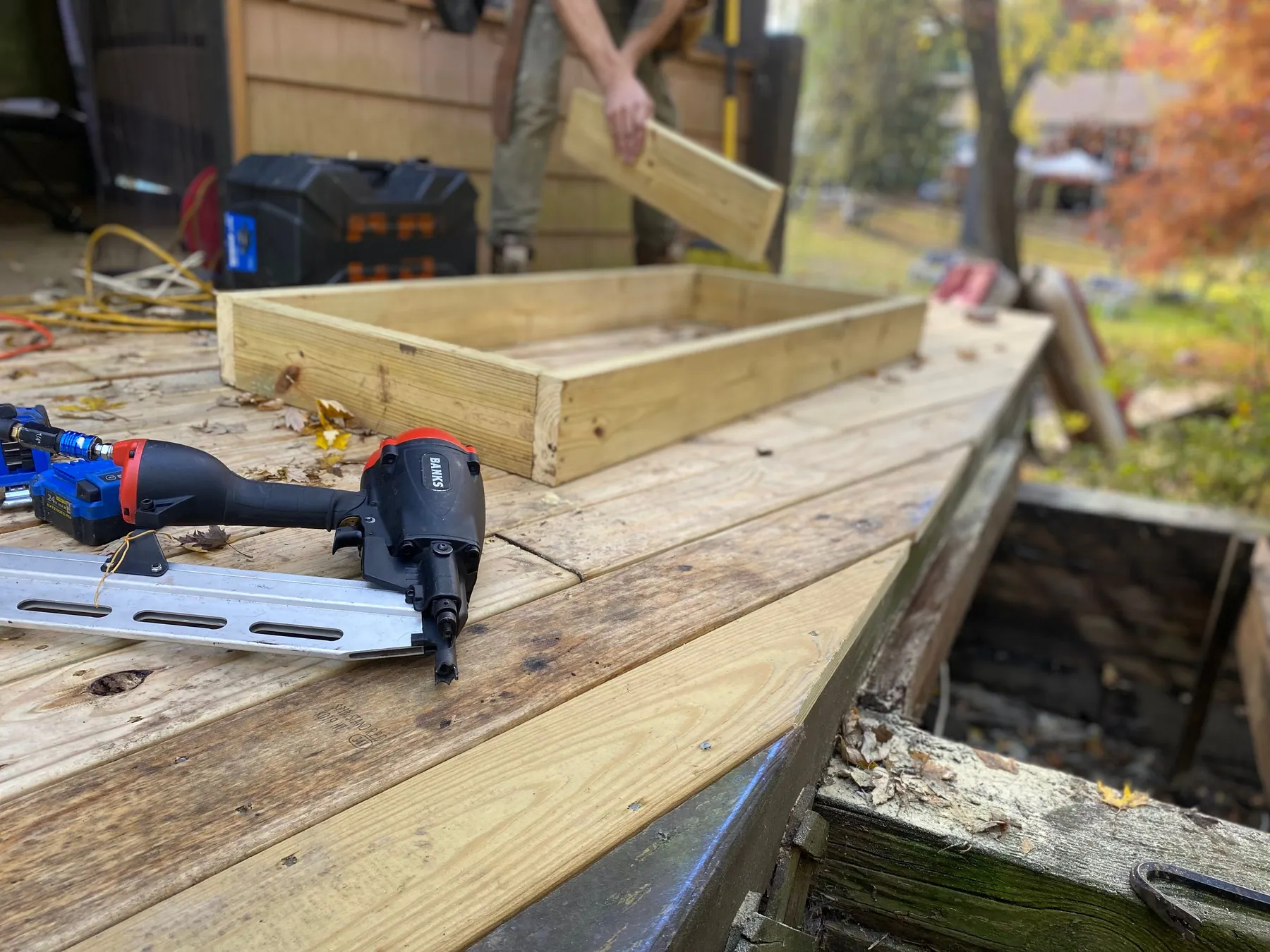 Residential deck boards and framing under construction with nail gun and tools