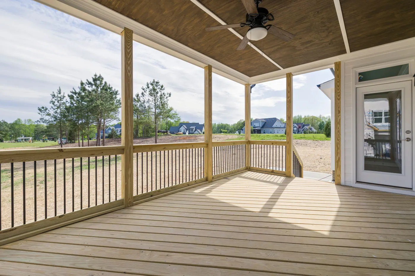 Finished wooden porch deck with railing and covered outdoor living space