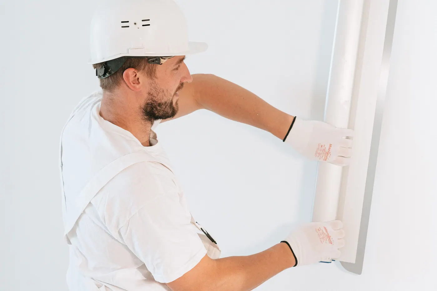 Worker installing a drywall panel during interior wall repair