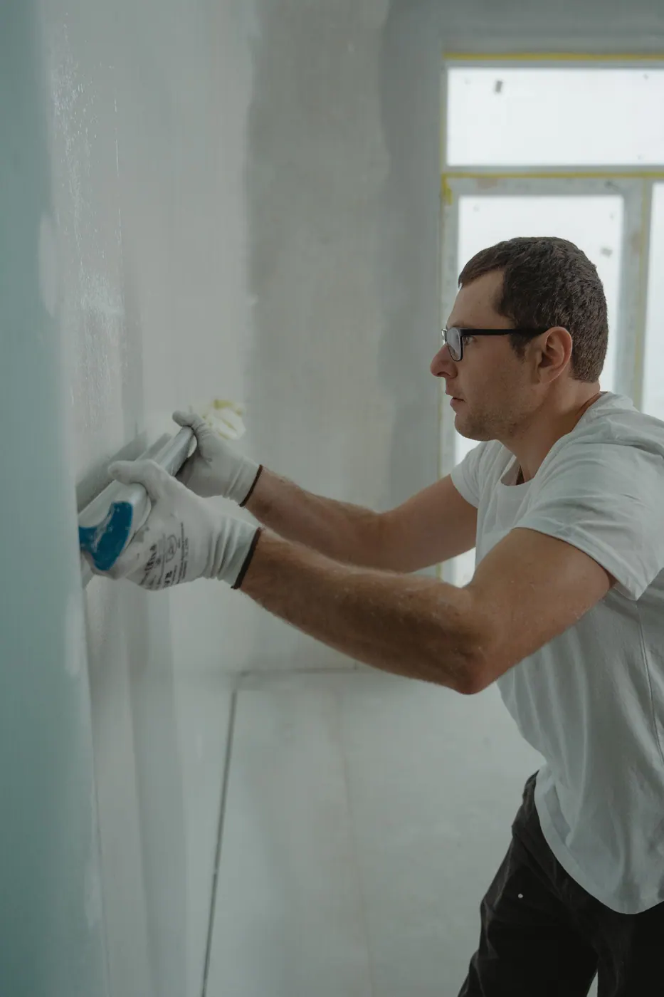 Worker smoothing joint compound on drywall for a paint-ready finish