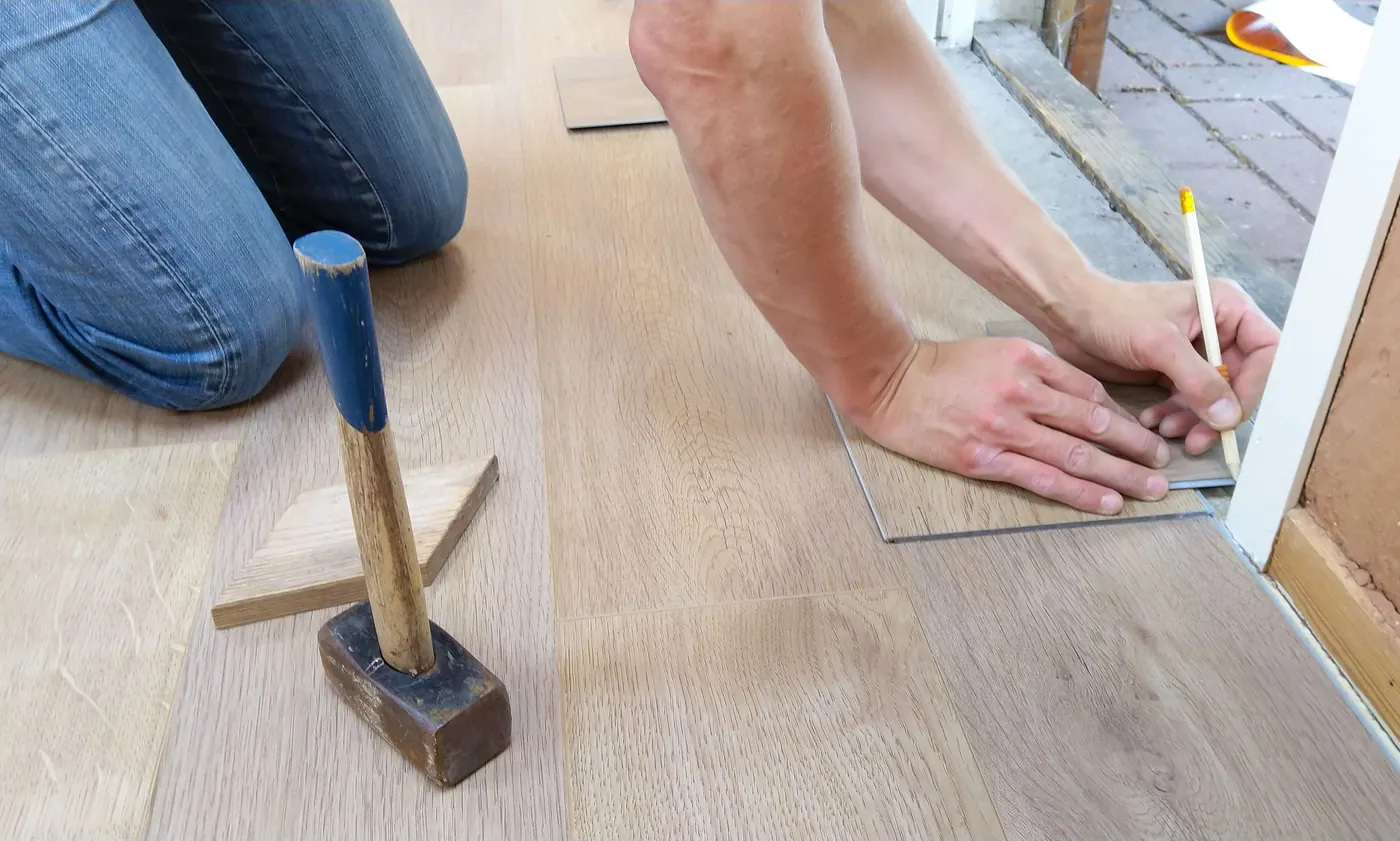 Flooring installer measuring a cut around a doorway during wood-look floor installation