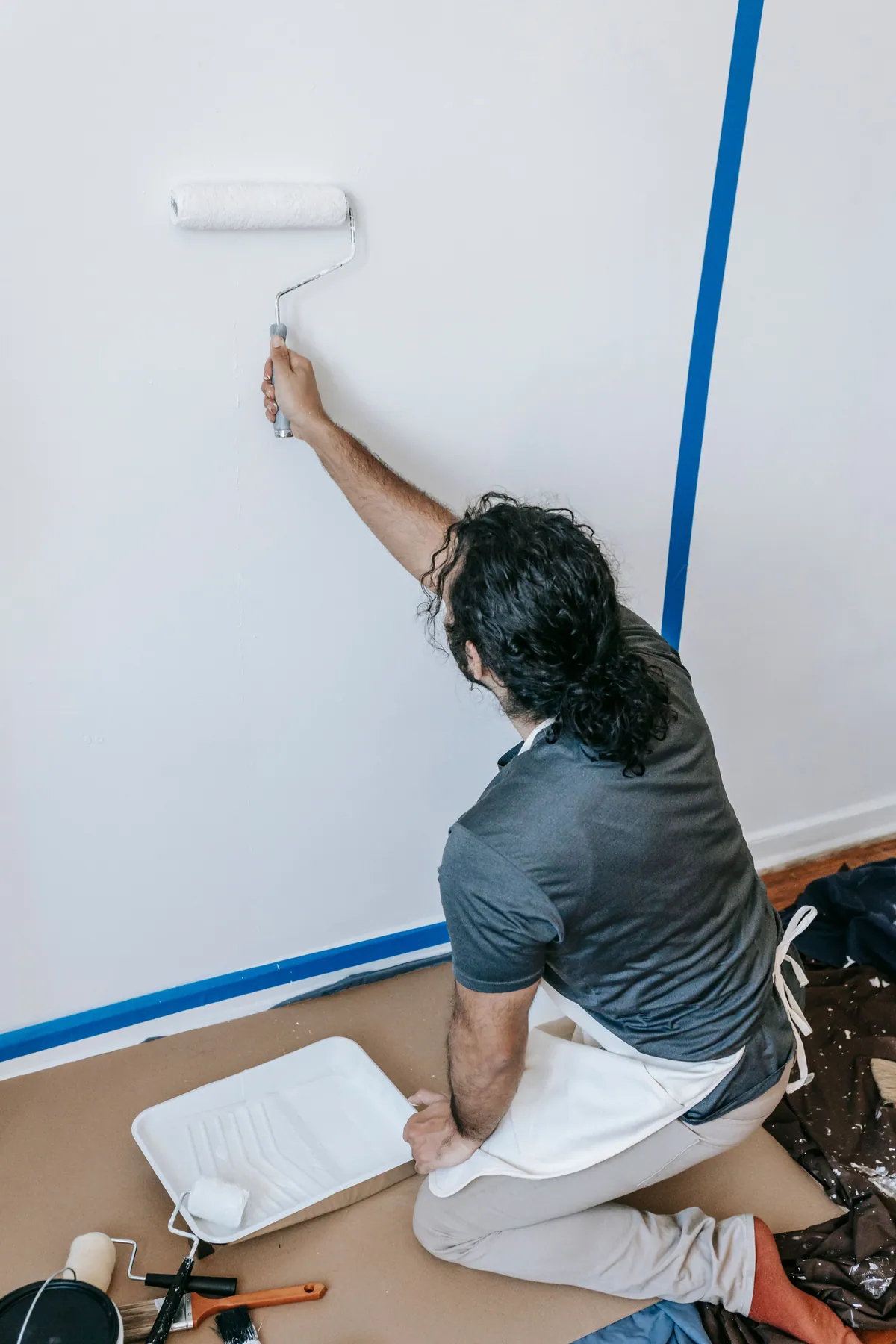 Interior painter rolling fresh paint onto a taped wall during room preparation