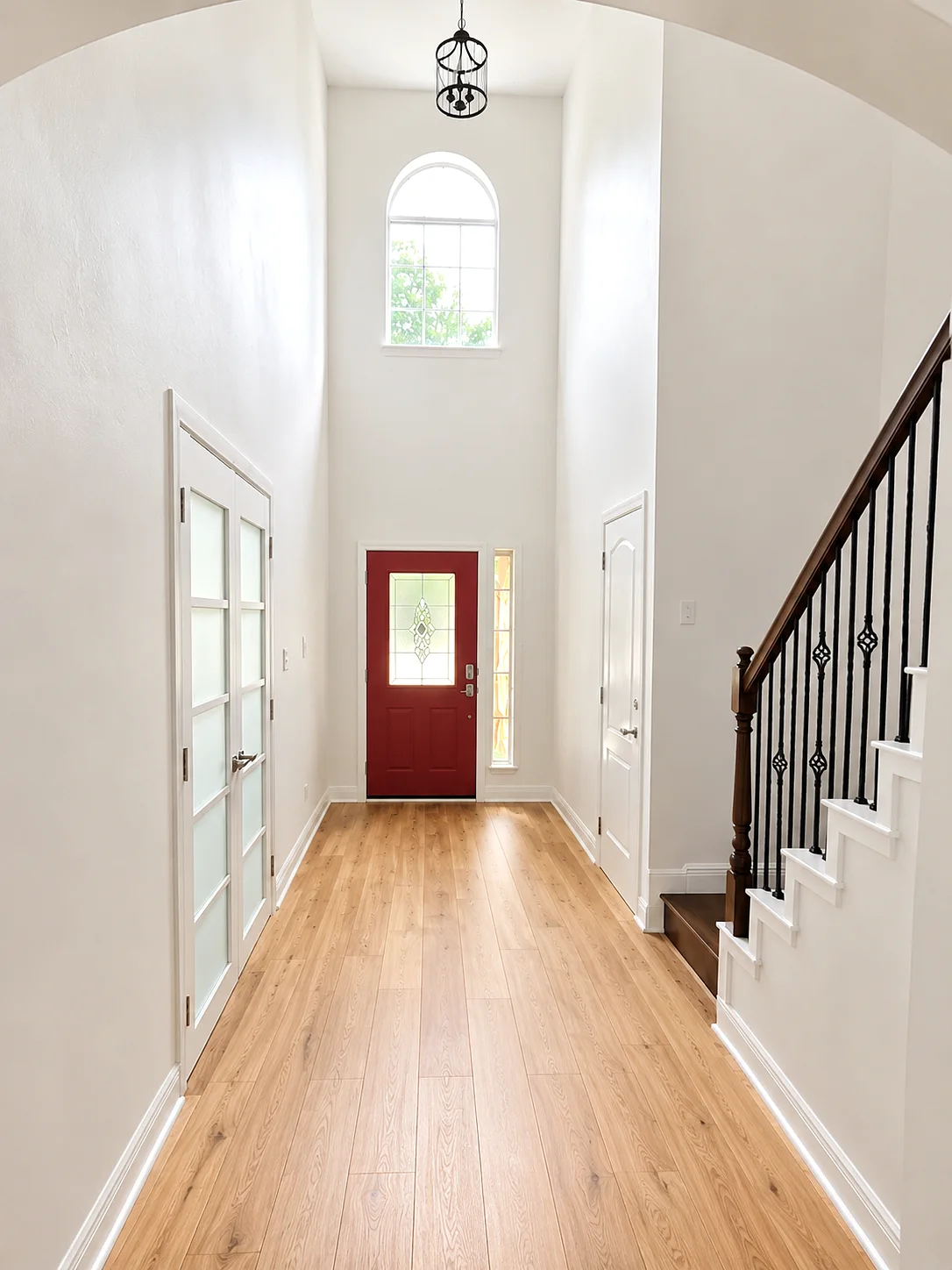 Finished Austin home entry with carefully painted white walls, trim, staircase, and red front door